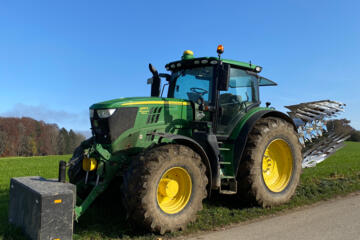 großer grüner Traktor mit Pflug auf dem Feld