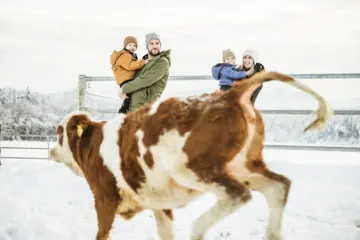 Familie bei dem Tiererlebnis im Winter auf dem Bauernhof im Chiemgau