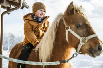 Ponyreiten am dem Bauernhof im Winter am Chiemsee